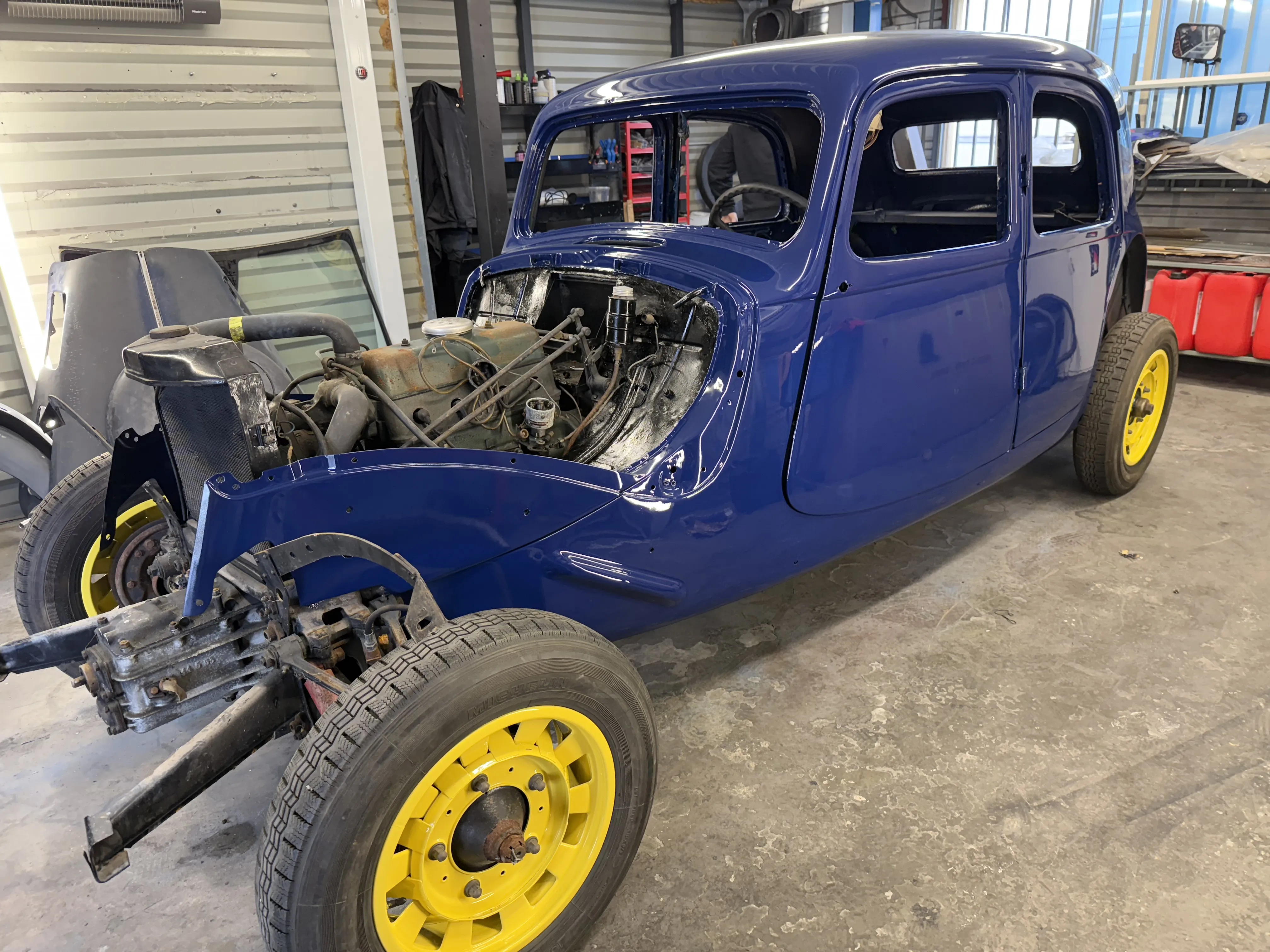 Citroën Traction Avant 11 BL de 1939 en cours de restauration, carrosserie bleu profond et jantes jaunes, sans ailes ni capot, dans l’atelier AutoMania Atelier à Eysines.